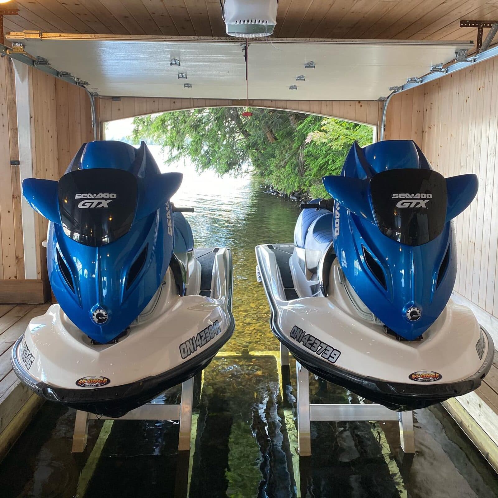 Two Sea-Doo jetskis in a lakeside boathouse
